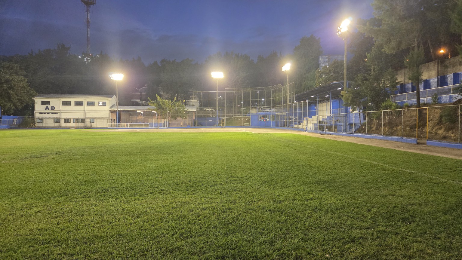 Campo de softbol iluminado bajo el cielo del anochecer